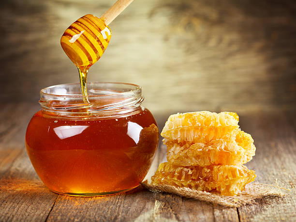 jar of honey with honeycomb on wooden table